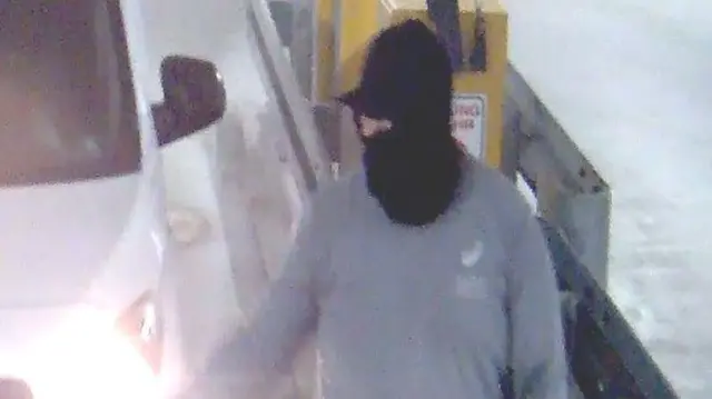 Um homem mascarado com uma van branca em uma imagem de circuito fechado de TV.