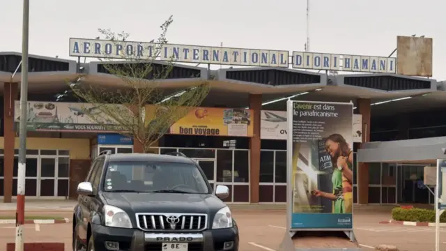 One car dey for di front of a foto of di Niamey airport