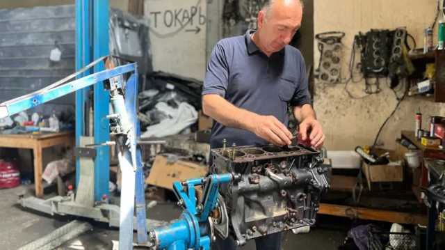 زا زا آندریاشویلی نزدیک به سه دهه است که موتور خودروها را تعمیر می‌کند، او در حال تعمیر یک موتور در کارگاه خود است.