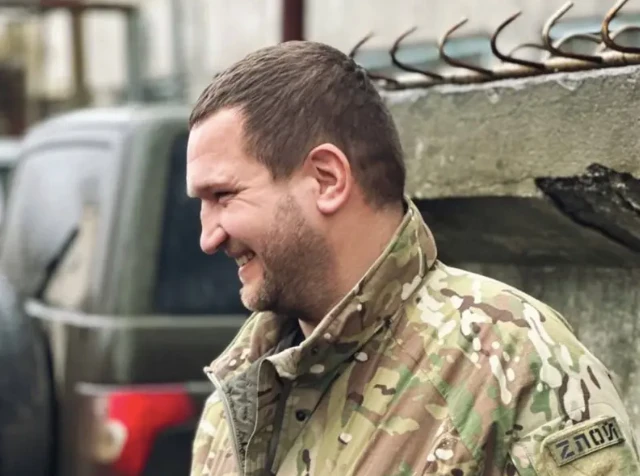 Человек в военной форме с шевроном "Злой" смеется