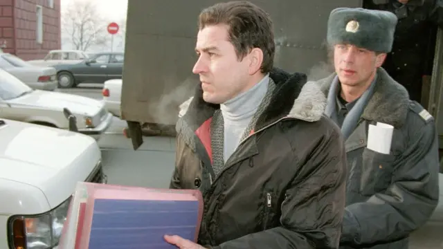 Military journalist Grigori Pasko (L) leaves a car escorted by a militiaman as he arrives at court in Vladivostok 21 January 1999