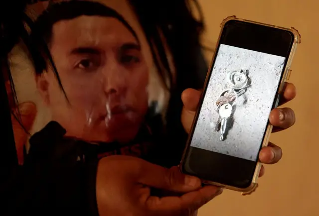 Una mujer sostiene un celular con una foto de unas llaves de su familiar desaparecido