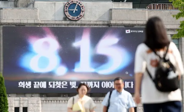 광복절 기념 문구 현수막 앞을 걷는 시민들