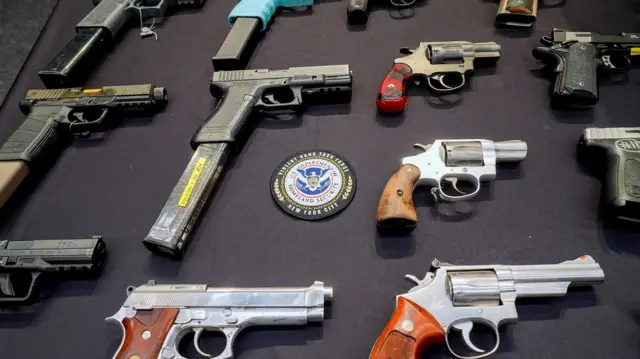 Unas doce armas cortas sobre una mesa negra y en el centro está el escudo de U.S. Department of Homeland Secutiry. New York City
