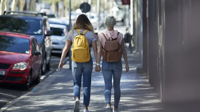 Casal caminha de mãos dadas na rua