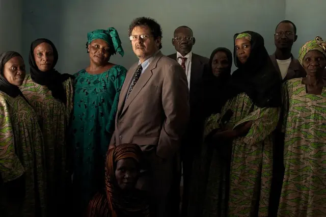 Reed Brody con un grupo de mujeres vestidas con ropa tradicional de Chad y dos hombres, uno de ellos vestido de traje y corbata
