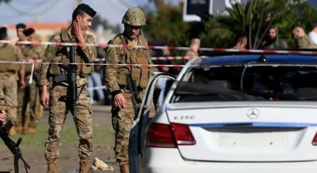 शनिवार को हुए एक ड्रोन हमले के बाद क्षतिग्रस्त कार का मुआयना करते सैनिक