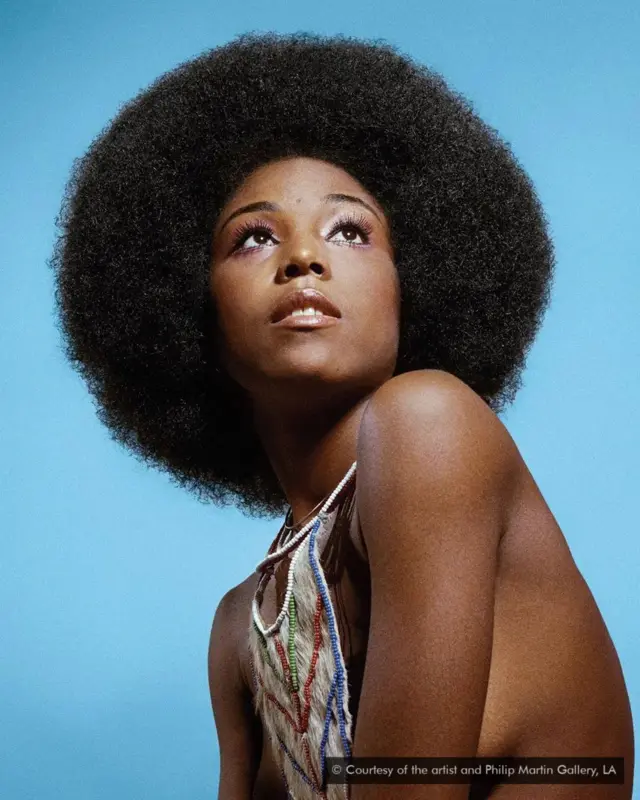 Une jeune fille noire, avec des cheveux touffus et un collier en perle au coup