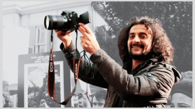 Fotoğrafta Hakan Tosun elinde bir fotoğraf makinesi tutuyor. 