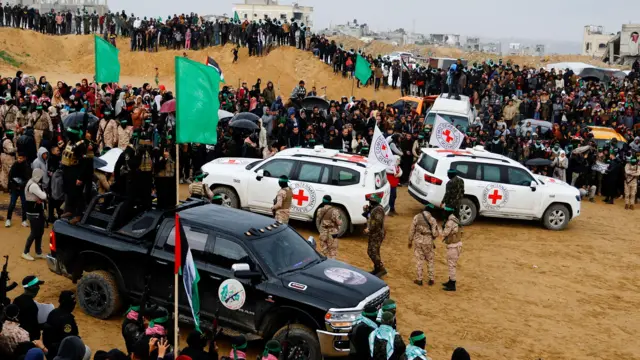 Mayaƙan Hamas da jami'an Red Cross kenan lokacin miƙa gawarwakin 'yan Isra'ila a Zirin Gaza. 