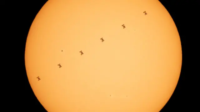 A silhueta da Estação Espacial Internacional contra o Sol