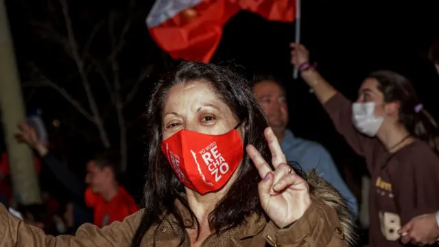 Una mujer lleva un mascarilla en la que se lee "rechazo"
