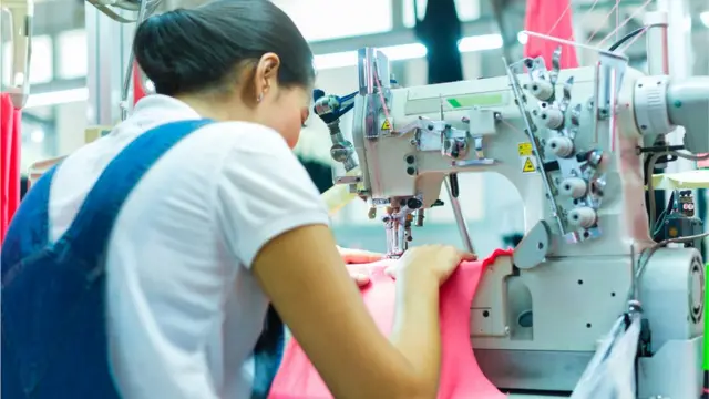 Women working on sewing machine.