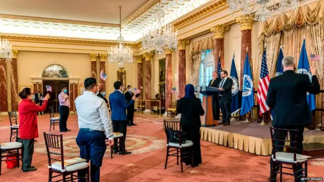 නව පුරවැසියන් පිරිසක් ඇමෙරිකානු ධජය අතැතිව එක්සත් ජනපද පුරවැසිභාවය සම්බන්ධ දිවුරුම් දෙන අවස්ථාවක්