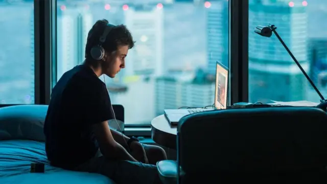 صبي يشاهد جهاز الكمبيوتر المحمول أثناء الليل