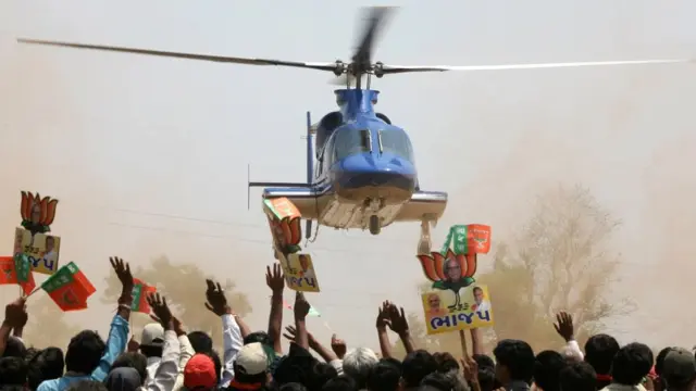 હેલિકૉપ્ટર ને આવકારતા લોકોની તસવીર