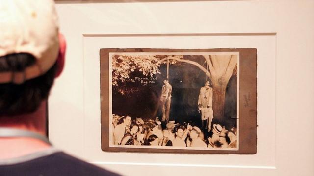 Em uma exposição, homem observa fotografia de linchamento nos Estados Unidos
