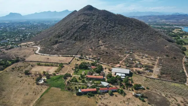 Aerial view of the seminary among fields at the foot of a mountain 