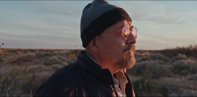 César Fierro mira hacia el horizonte en una de las tomas del documental "La libertad de Fierro". La luz del atardecer le ilumina el rostro.