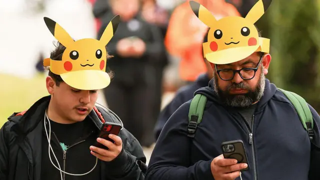 Asistentes con gorros de Pikachu juegan Pokémon GO en sus teléfonos inteligentes durante el evento presencial Pokémon GO Tour.