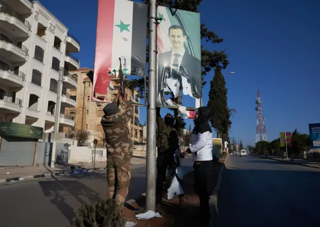 Forces from the opposition factions tear down a picture of the Syrian President in Aleppo.