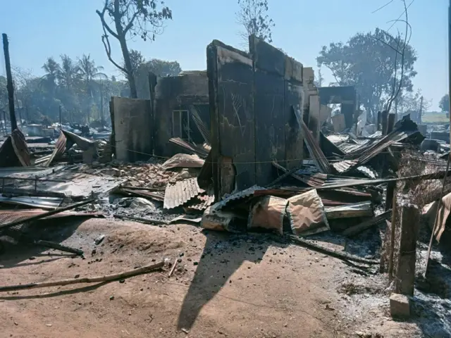 မီးလောင်ပြာကျလုနီးပျက်စီးကာ သွပ်မိုးတွေ မြေပေါ်ကျ တွန့်လိမ်နေတဲ့ အိမ်တစ်လုံး