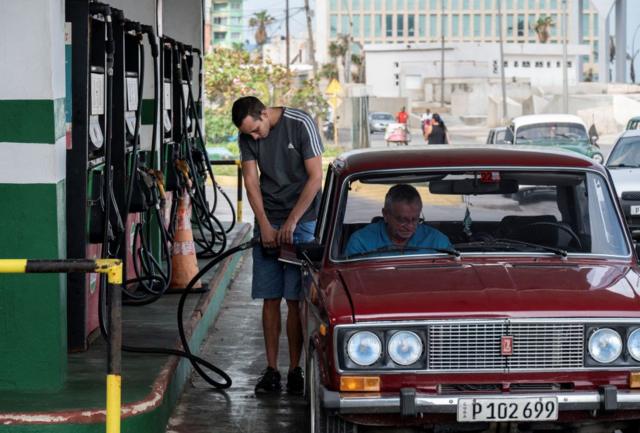 Homem abastecendo o carro em posto de gasolina em Cuba