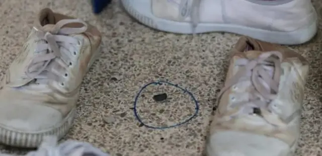 Bullet wey dey in between two white canvas shoes