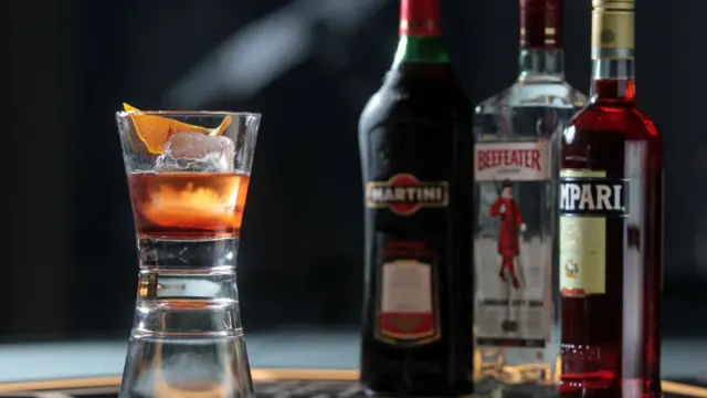 стакан с негрони и бутылки с его ингредиентами