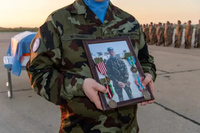 زميل الجندي الإيرلندي، شون روني، الذي قتل خلال عمله في بعثة حفظ السلام التابعة للأمم المتحدة في لبنان يحمل صورته