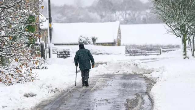 Mężczyzna idzie wzdłuż drogi po intensywnych nocnych opadach śniegu