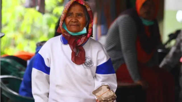 Seorang ibu yang mengungsi, membawa makanan yang dibagikan relawan di tempat pengungsian letusan Gunung Semeru di SDN Supiturang 4, Pronojiwo, Lumajang, Jawa Timur, Senin (06/12).