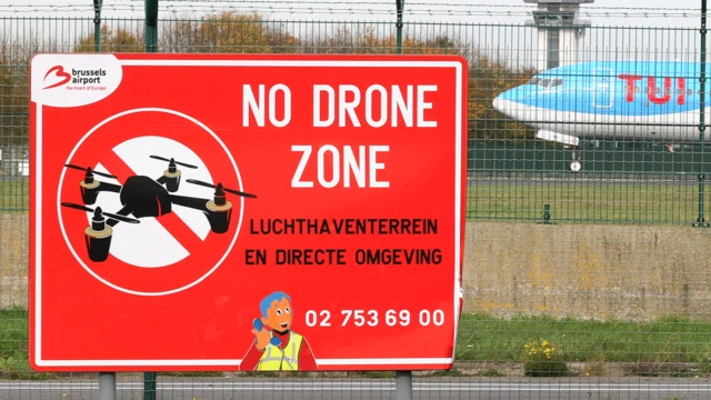 Літак приземляється на злітну смугу поруч із табличкою "Зона, вільна від дронів"