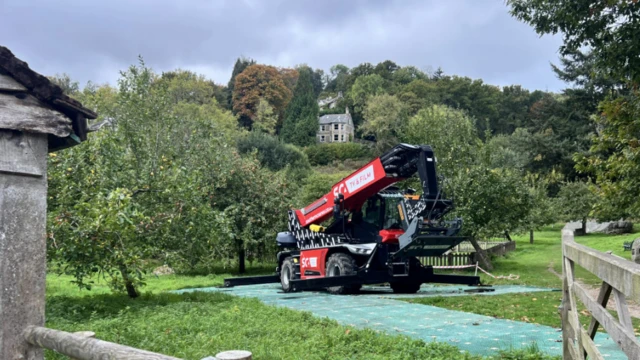 A production vehicle in a green field, possibly near a filming location.