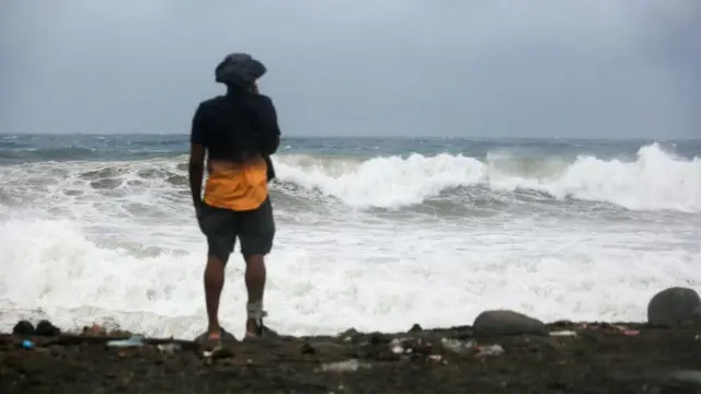 Un hombre mira hacia las fuertes olas del mar en Jamaica