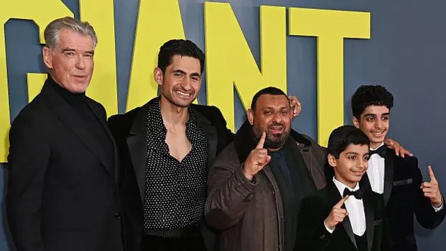 Fotografía de grupo de (de izquierda a derecha) Pierce Brosnan, Amir El-Masry, Prince Naseem, Ghaith Saleh y Ali Saleh posando juntos en una proyección frente al título de Gigante sobre un fondo.