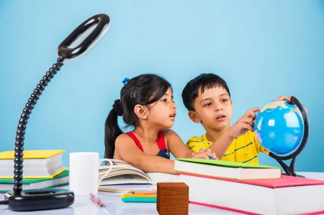 స్టడీ టేబుల్ మీద గ్లోబును పరిశీలిస్తున్న ఇద్దరు చిన్నారులు