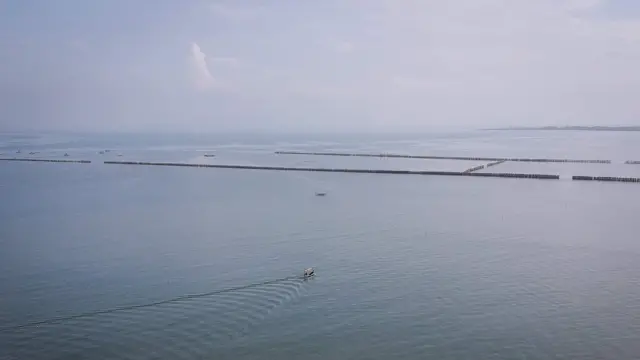 Foto udara perahu nelayan melintas di dekat pagar laut di Pantai Anom, Desa Kohod, Kabupaten Tangerang, Banten, Jumat (24/1/2025). Kementerian Agraria dan Tata Ruang/Badan Pertanahan Negara membatalkan 50 Sertifikat Hak Guna Bangunan (SHGB) dan Sertifikat Hak Milik (SHM) yang berada di desa tersebut sebagai tindak lanjut adanya pagar bambu ilegal di perairan Kabupaten Tangerang. 