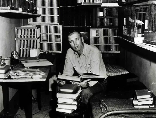 Burt Lancaster en la película "El hombre de Alcatraz" en una celda con jaulas de pájaros.