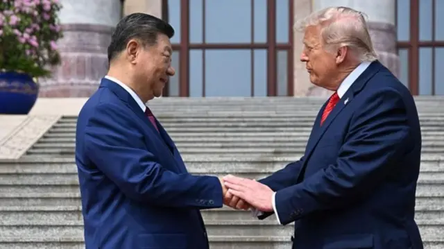 ダークスーツ姿の両首脳が向き合って右手で握手している。トランプ氏は左手も習氏の手にのせている