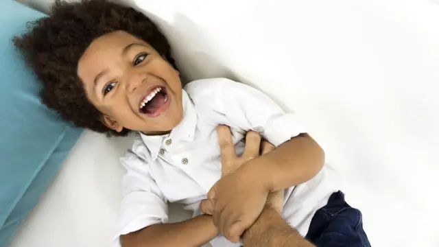 Niño de unos 6 años riéndose al recibir cosquillas.