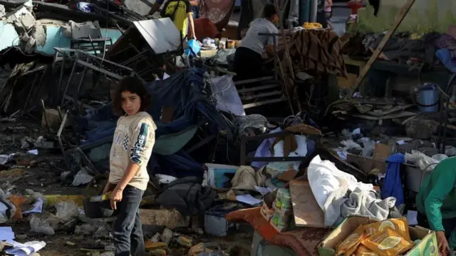 Devojčica stoji među ruševinama škole u Gazi koja je pogođena tokom izraelskog vazdušnog napada