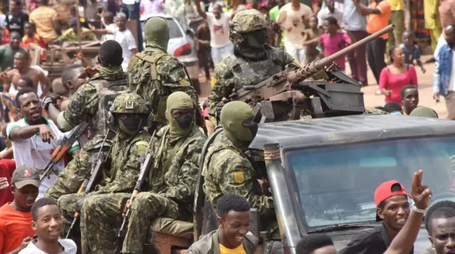 Les gens célèbrent dans les rues avec des membres des forces armées guinéennes après l'arrestation du président guinéen, Alpha Condé, lors du coup d'État à Conakry, le 5 septembre 2021.