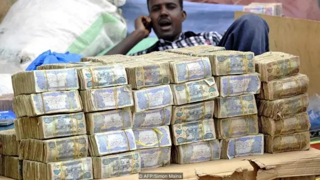 Currency Note trader of Somaliland sitting on heaps of Somaliland Shilings, as 9,000 Somaliland Shilings equals to one US Dollar
