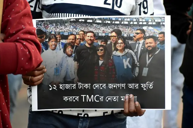 বিজেপির যুব সংগঠন রবিবার বিক্ষোভ দেখায় সামাজিক মাধ্যমে ছড়িয়ে পড়া এই ছবিটি নিয়ে : মেসির ডানে মন্ত্রী অরূপ বিশ্বাসের এবং বামে মমতা ব্যানার্জীর পরিবারের সদস্যরা। মেসির পিছনে দেখা যাচ্ছে মন্ত্রীকেও