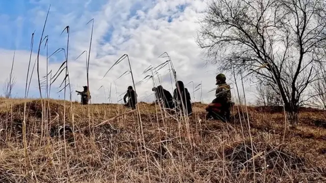 Les soldats se déplacent dans les hautes herbes.