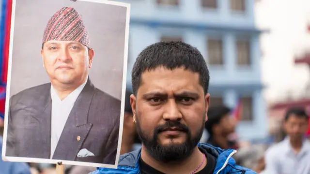 आंदोलन के दौरान काठमांडू के त्रिभुवन अंतर्राष्ट्रीय हवाई अड्डे पर पूर्व राजा ज्ञानेंद्र शाह की तस्वीर लिए एक समर्थक.