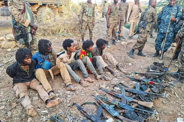 የታጣቂ ቡድኑ አባላት ናቸው የተባሉ ሰዎች እጃቸው ወደ ኋላ ታስሮ እና መሬት ላይ ቁጭ ብለው