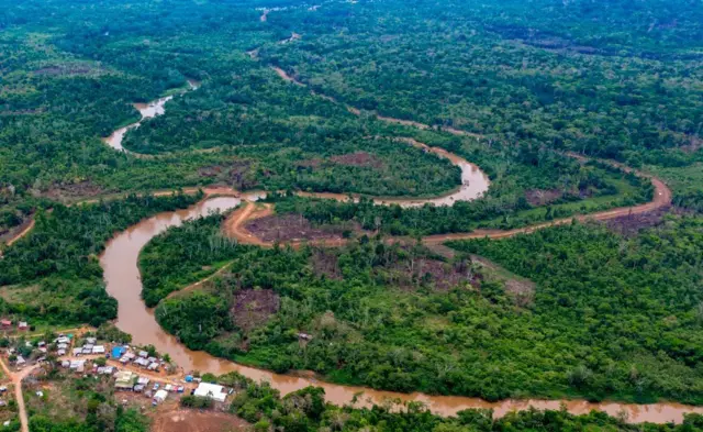 Вид с воздуха на провинцию Дарьен, Панама: река с мутной желтовато-коричневой водой петляет по лесистой местности с грунтовой дорогой

