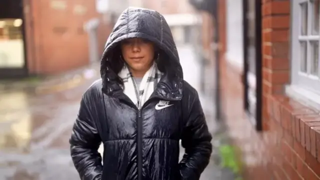 Une jeune fille qui porte un capuchon noir